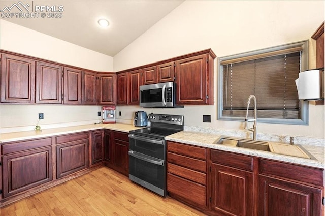 kitchen featuring sink, light wood-type flooring, stainless steel appliances, and vaulted ceiling