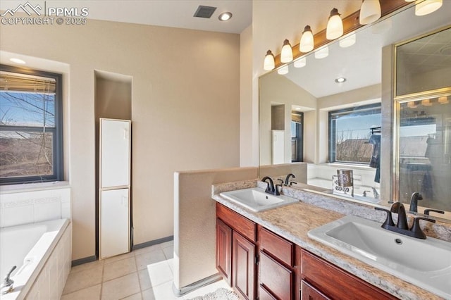 bathroom with tile patterned floors, vanity, and tiled tub