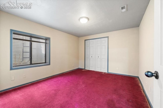 unfurnished bedroom with carpet, a textured ceiling, and a closet