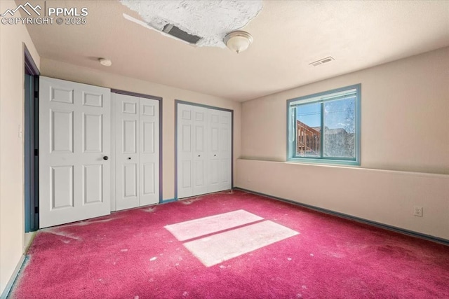 unfurnished bedroom featuring carpet flooring and two closets