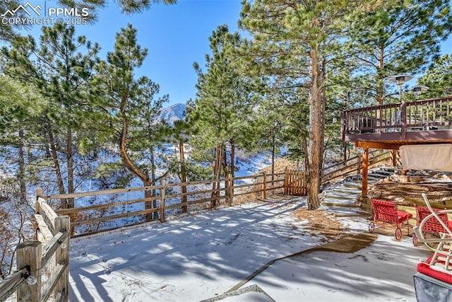 snowy yard with a deck with mountain view