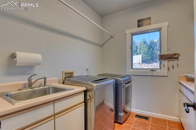 washroom with cabinets, light tile patterned floors, washer and clothes dryer, and sink