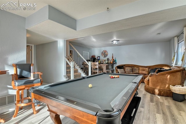 playroom featuring bar, light hardwood / wood-style floors, and pool table