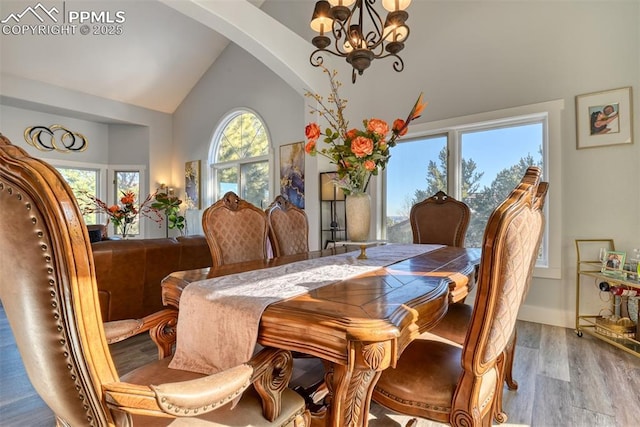 dining space featuring light hardwood / wood-style floors, lofted ceiling, and an inviting chandelier