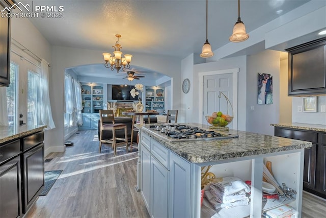 kitchen with built in shelves, decorative light fixtures, a kitchen island, and stainless steel gas stovetop