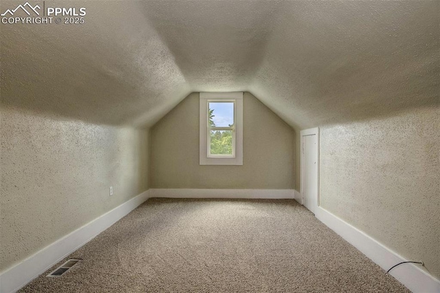 bonus room with carpet, lofted ceiling, and a textured ceiling