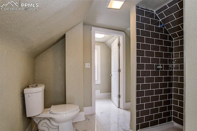 bathroom featuring toilet, a textured ceiling, a tile shower, and vaulted ceiling