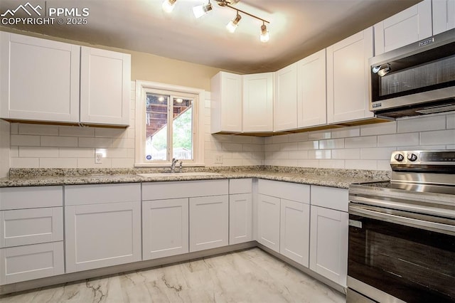 kitchen with backsplash, light stone counters, stainless steel appliances, sink, and white cabinets