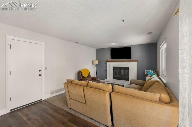 living room featuring a fireplace, a textured ceiling, and dark hardwood / wood-style flooring