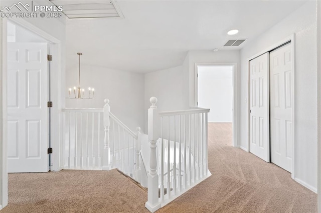 hall with an inviting chandelier and carpet floors