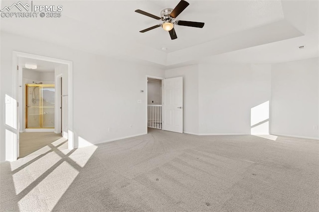 carpeted empty room featuring a raised ceiling and ceiling fan