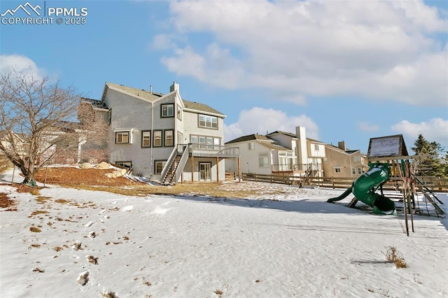 snow covered rear of property with a playground