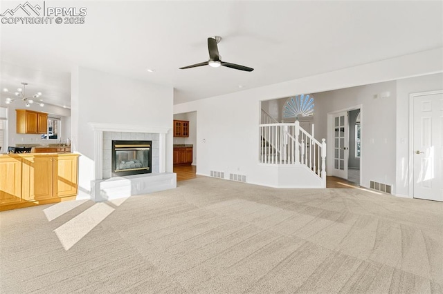 unfurnished living room featuring a tiled fireplace, ceiling fan, and light carpet