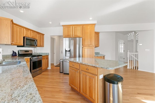 kitchen featuring sink, a center island, light stone countertops, and appliances with stainless steel finishes