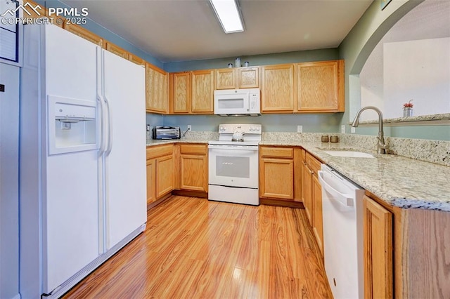 kitchen featuring white appliances, sink, light stone countertops, light wood-type flooring, and light brown cabinetry