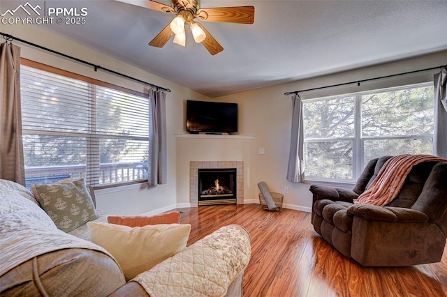 living room featuring ceiling fan, a fireplace, and light hardwood / wood-style floors