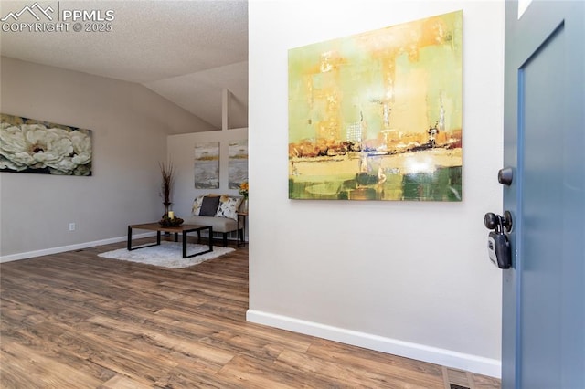 foyer entrance with wood-type flooring, lofted ceiling, and a textured ceiling