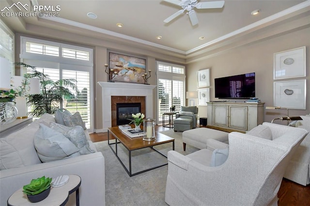 living room featuring crown molding, a tray ceiling, a high end fireplace, and a healthy amount of sunlight