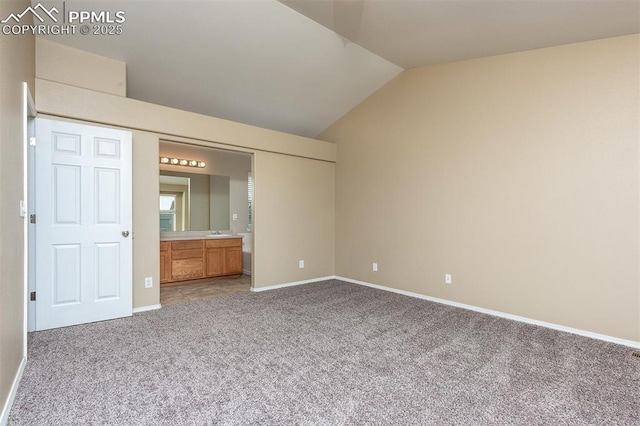 unfurnished bedroom featuring carpet flooring, connected bathroom, and vaulted ceiling