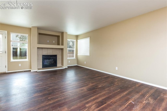 unfurnished living room with dark wood-type flooring and a tile fireplace