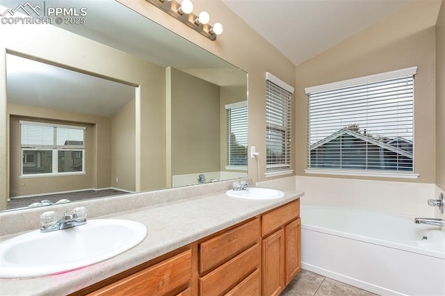 bathroom featuring tile patterned flooring, vanity, a tub, and lofted ceiling