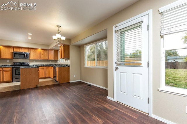 kitchen featuring appliances with stainless steel finishes, dark hardwood / wood-style flooring, sink, pendant lighting, and a notable chandelier