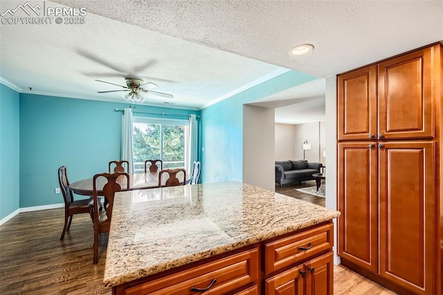 kitchen featuring ceiling fan, light stone countertops, ornamental molding, and light hardwood / wood-style flooring