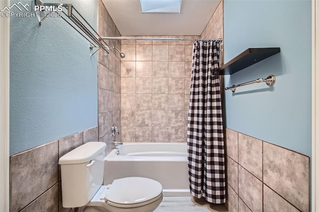 bathroom featuring shower / bath combination with curtain, tile walls, and toilet