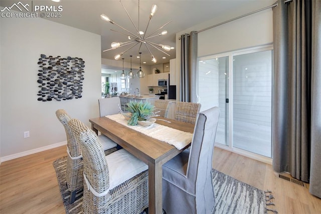 dining space featuring light hardwood / wood-style floors and an inviting chandelier