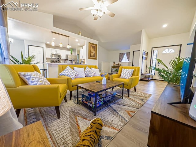 living room featuring ceiling fan, lofted ceiling, and light wood-type flooring