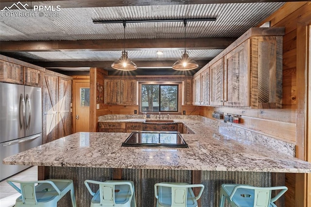 kitchen featuring pendant lighting, stainless steel fridge, black electric cooktop, and wood walls