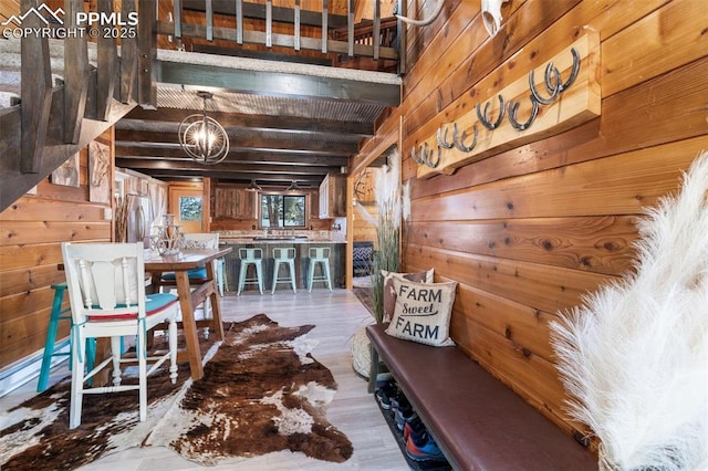 dining area featuring hardwood / wood-style flooring, a chandelier, beam ceiling, and wood walls