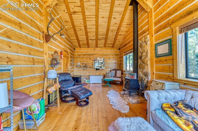 living area with wood walls, a wood stove, vaulted ceiling with beams, hardwood / wood-style flooring, and wood ceiling