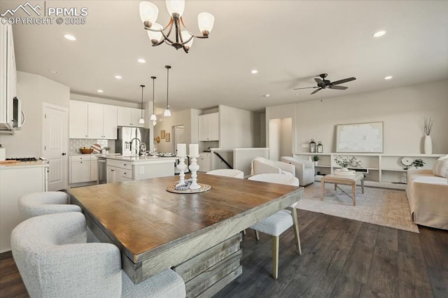 dining space with dark hardwood / wood-style flooring, ceiling fan with notable chandelier, and sink