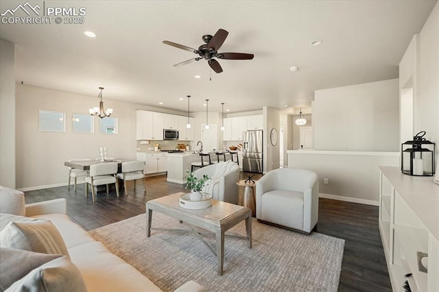 living room with ceiling fan with notable chandelier, dark hardwood / wood-style flooring, and sink