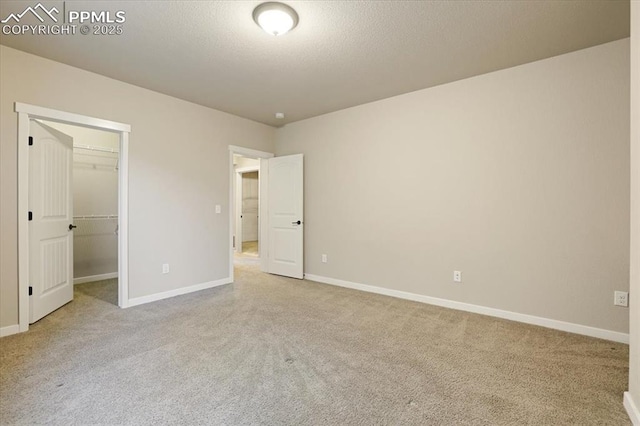 unfurnished bedroom with a spacious closet, light carpet, and a closet