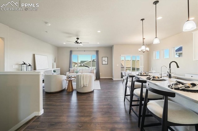 living room with dark hardwood / wood-style flooring, plenty of natural light, ceiling fan with notable chandelier, and sink