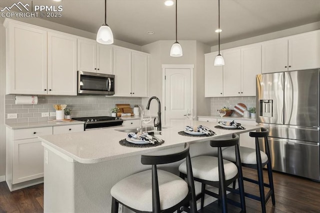 kitchen with white cabinets, sink, stainless steel appliances, and an island with sink