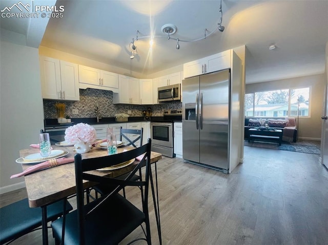 kitchen with backsplash, stainless steel appliances, sink, light hardwood / wood-style floors, and white cabinetry