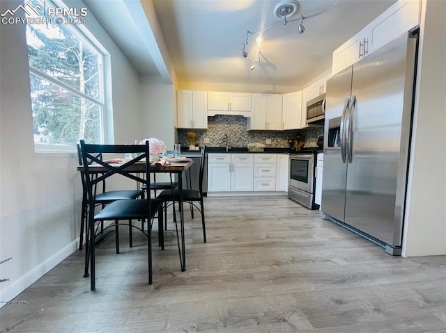 kitchen featuring backsplash, white cabinets, sink, appliances with stainless steel finishes, and light hardwood / wood-style floors