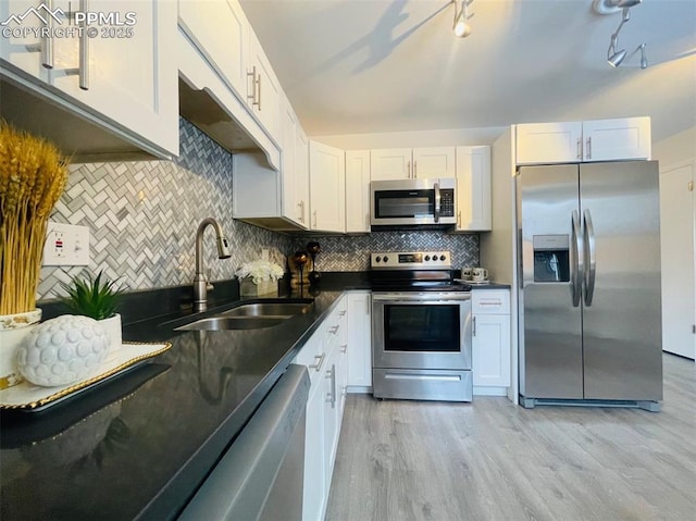 kitchen featuring sink, stainless steel appliances, light hardwood / wood-style flooring, backsplash, and white cabinets