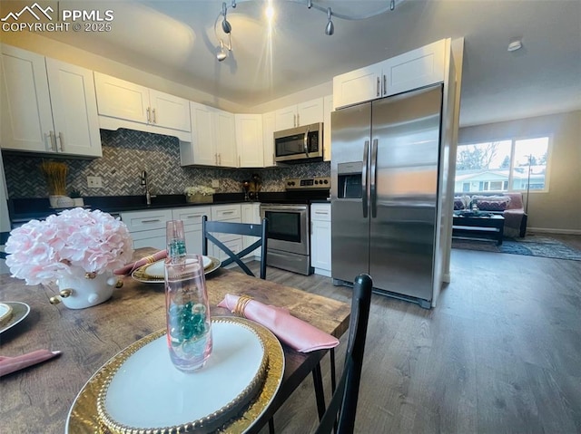 kitchen featuring decorative backsplash, dark hardwood / wood-style flooring, stainless steel appliances, sink, and white cabinetry