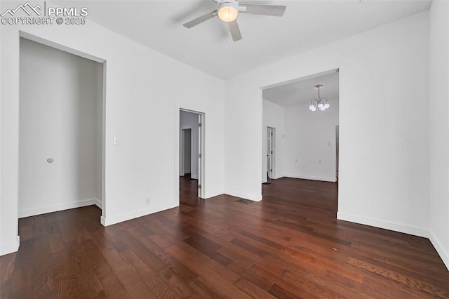 empty room featuring ceiling fan with notable chandelier and dark hardwood / wood-style flooring