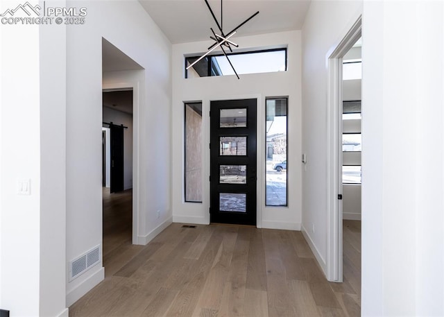 foyer entrance with a barn door, an inviting chandelier, and light hardwood / wood-style flooring