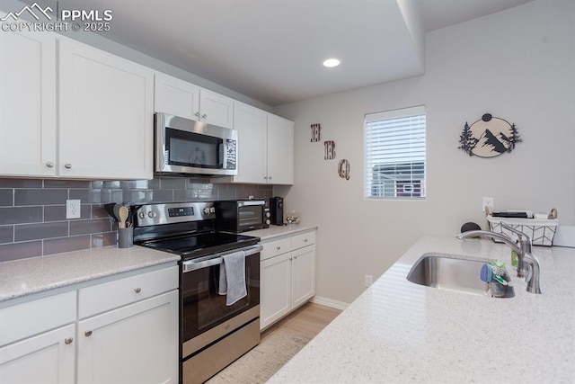 kitchen with white cabinets, sink, stainless steel appliances, and tasteful backsplash