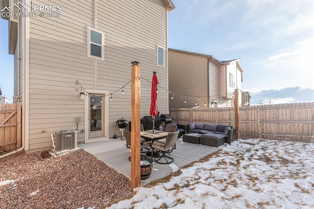 snow covered back of property with central air condition unit, a patio area, and an outdoor living space