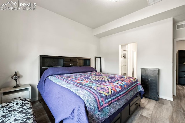 bedroom with hardwood / wood-style floors and connected bathroom