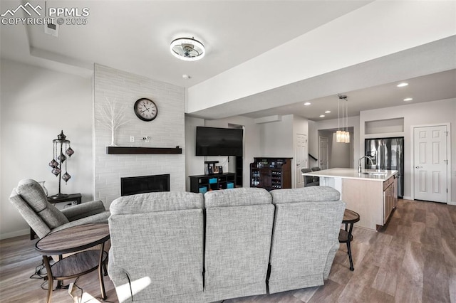 living room with sink, a large fireplace, and hardwood / wood-style flooring