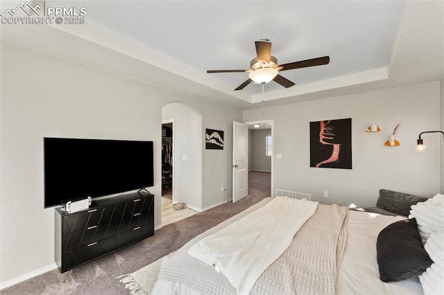 carpeted bedroom with ceiling fan and a tray ceiling