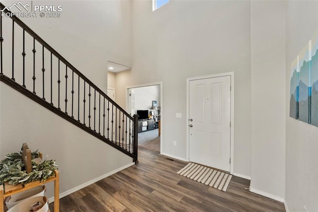 foyer with a towering ceiling and dark wood-type flooring